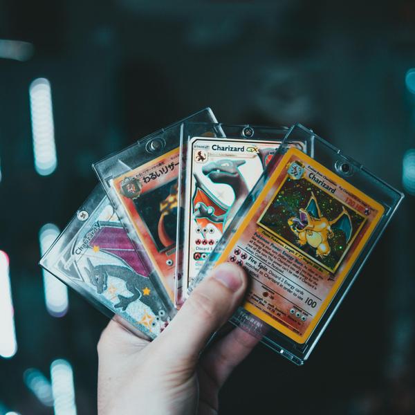 A hand holds four Pokémon cards fanned out.