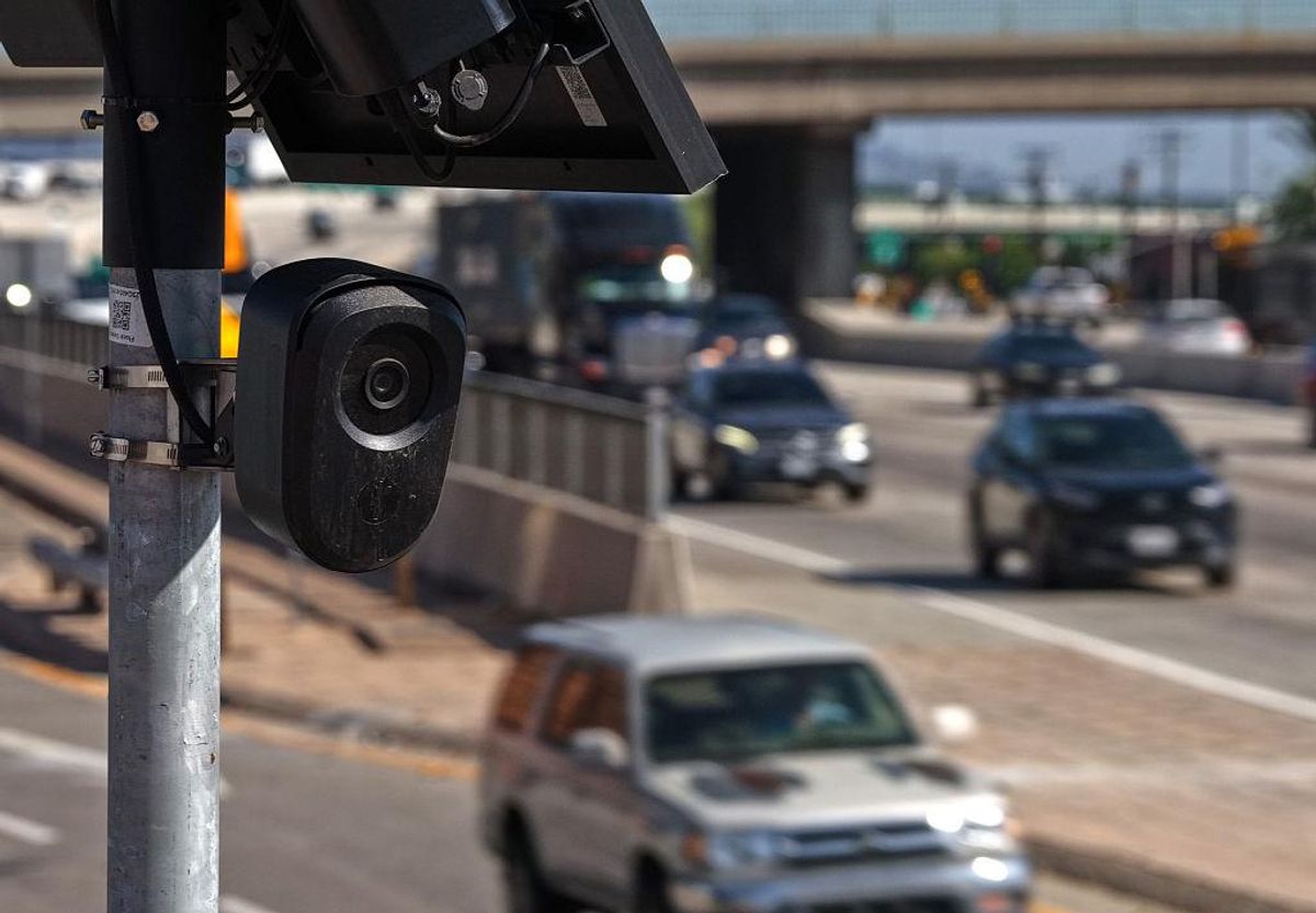 A license plate reader camera faces towards a busy highway.