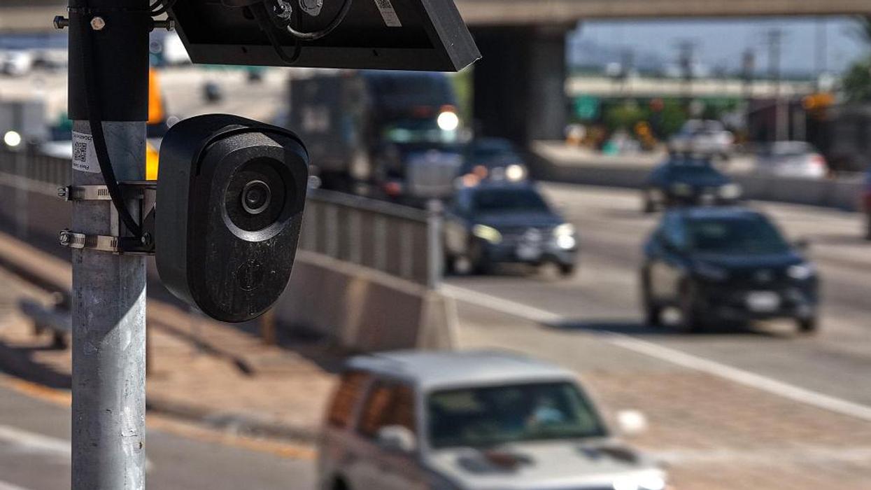 A license plate reader camera faces towards a busy highway.