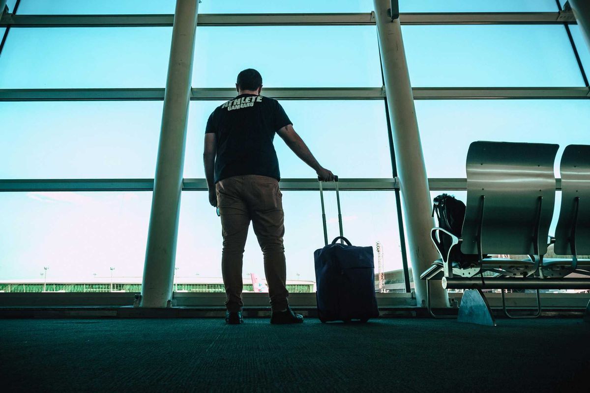 A man at the airport stares out the window at the airplanes