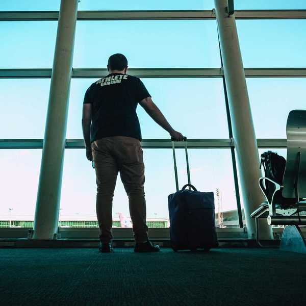 A man at the airport stares out the window at the airplanes