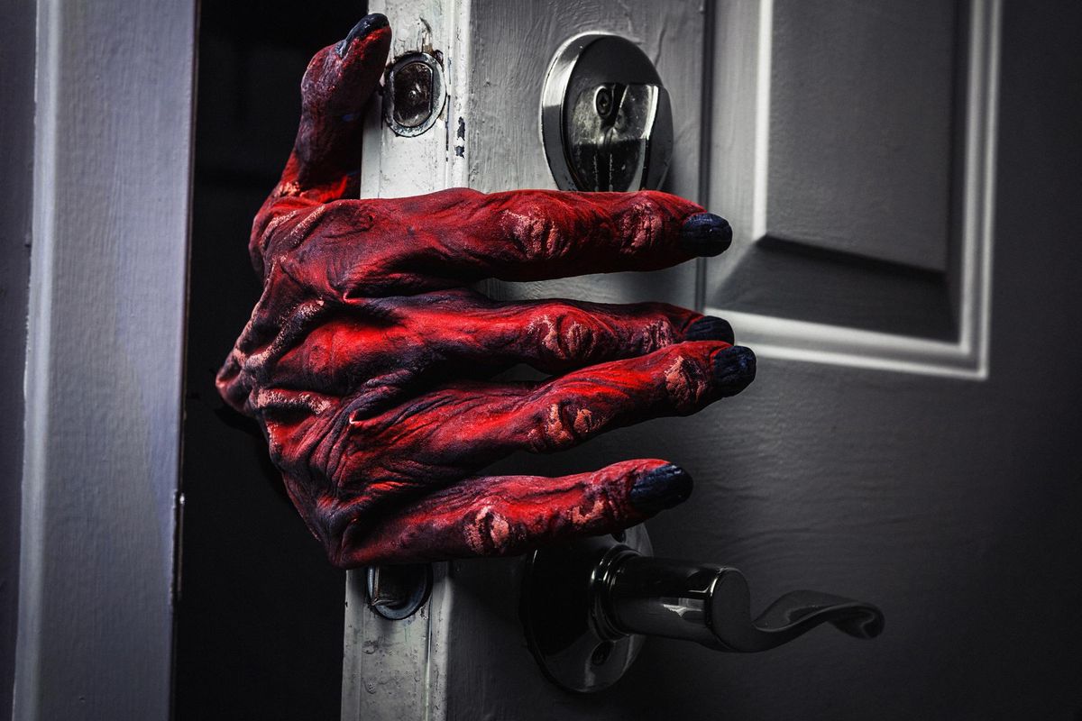 A monster hand reaches around a door frame to open it