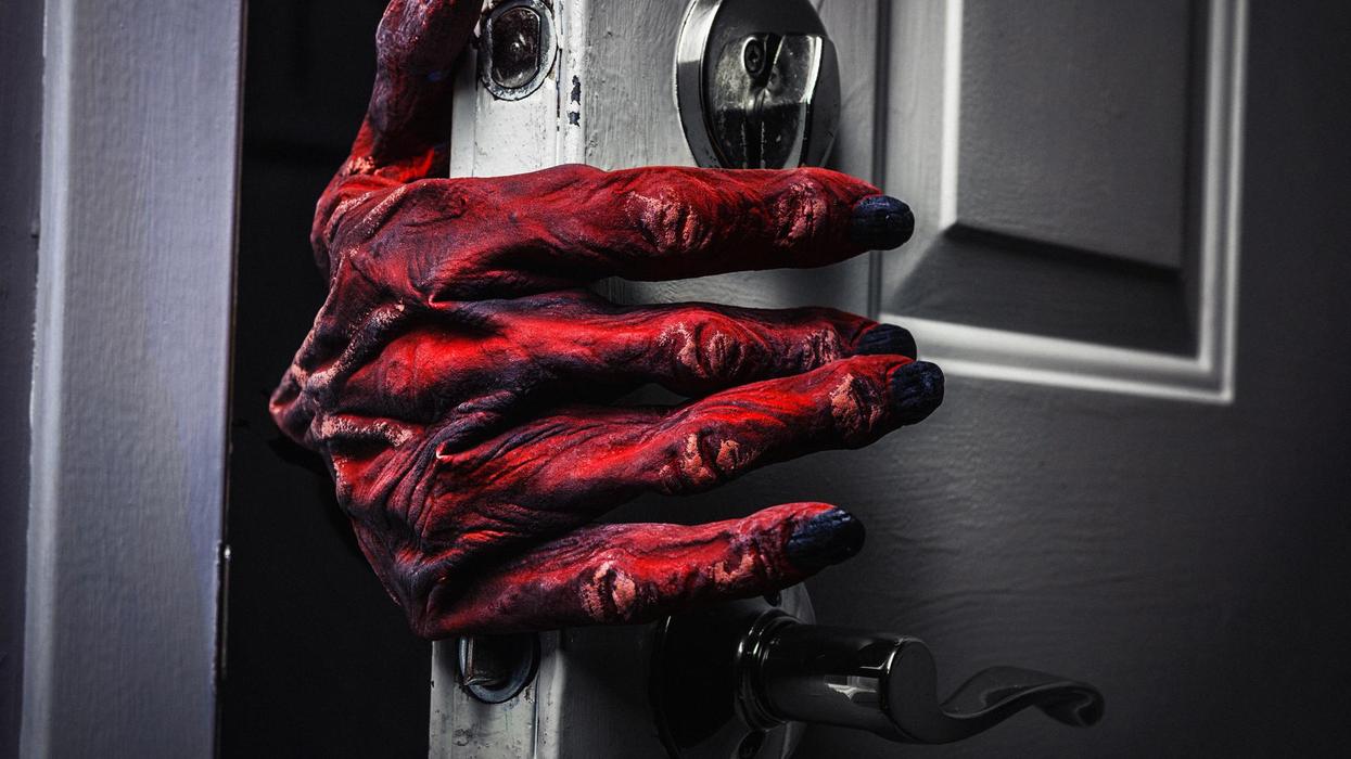 A monster hand reaches around a door frame to open it