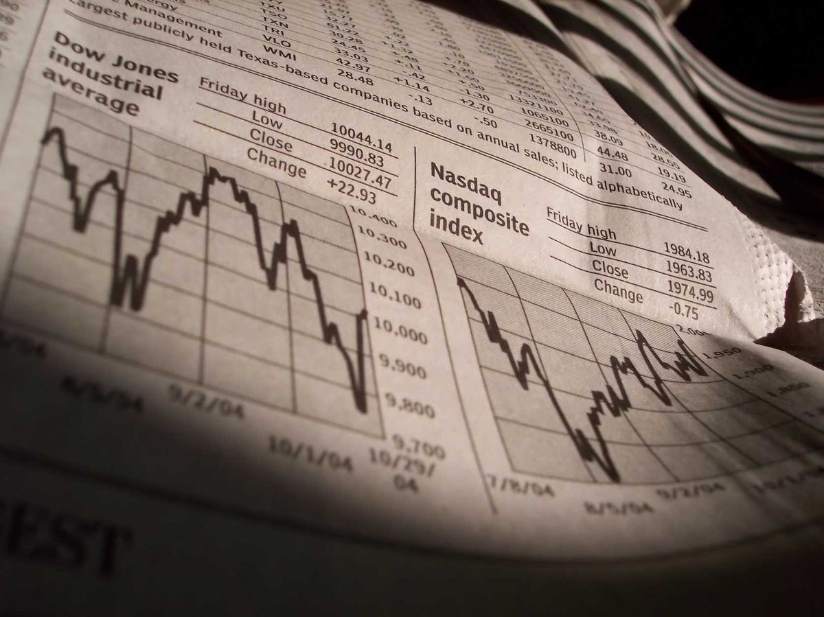 A newspaper shows Dow and Nasdaq index performance on a certain day