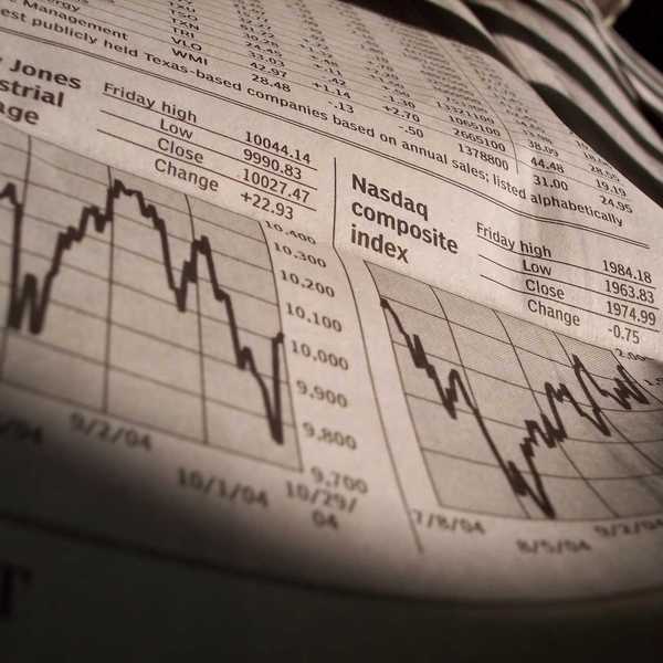 A newspaper shows Dow and Nasdaq index performance on a certain day