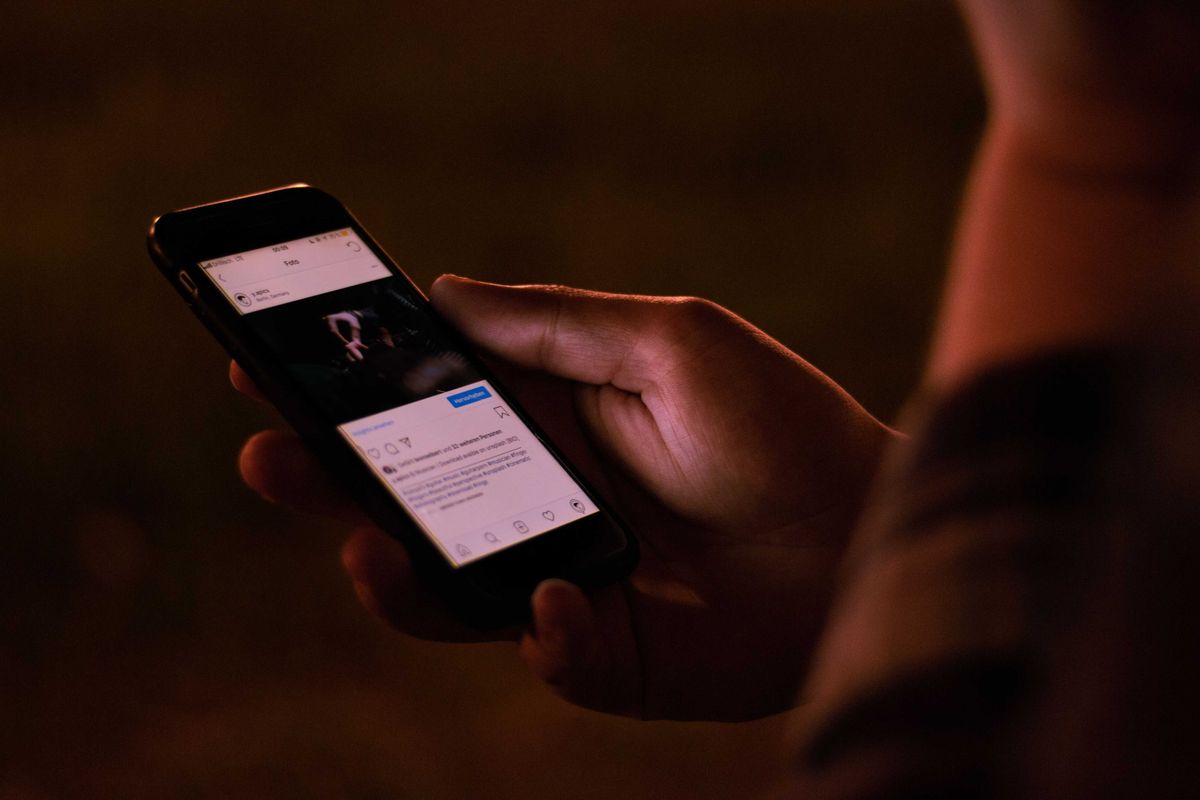 A person interacts with a smartphone in a dimly lit setting.
