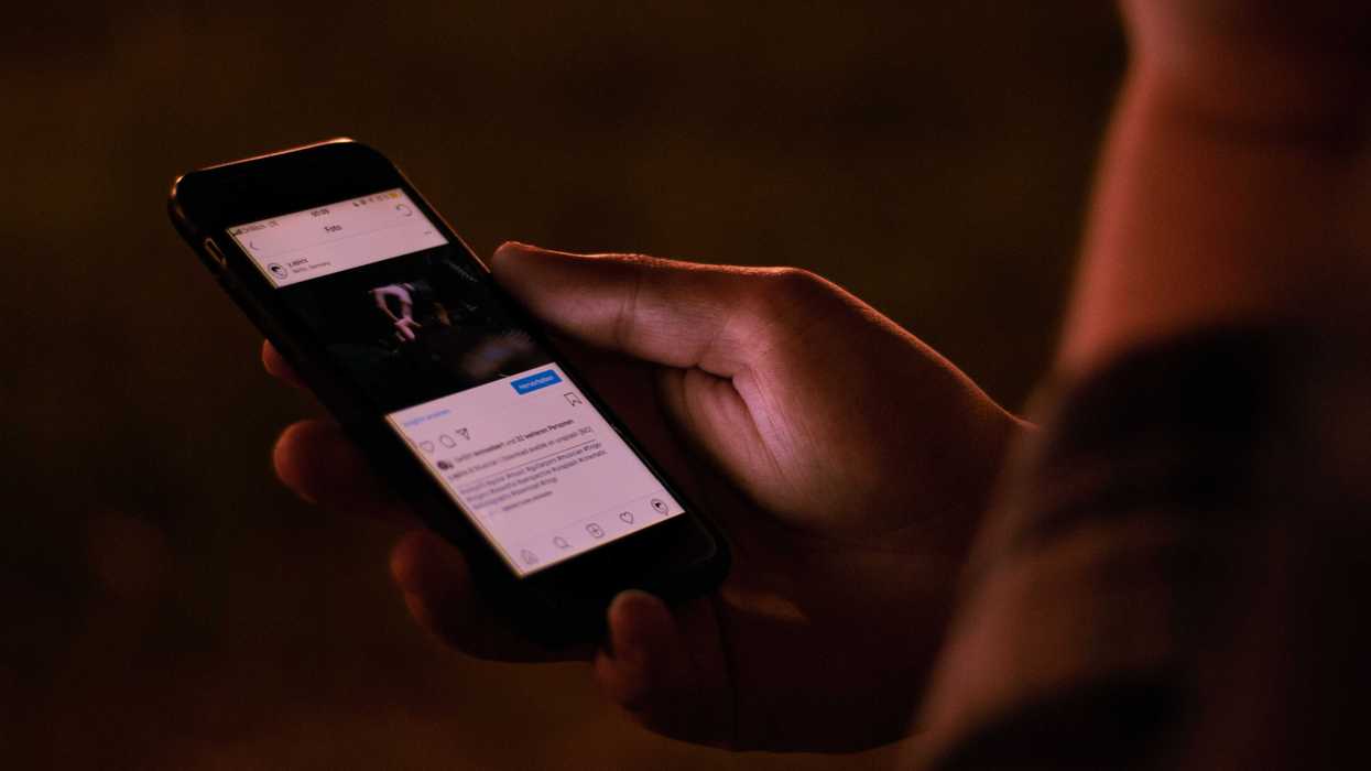 A person interacts with a smartphone in a dimly lit setting.