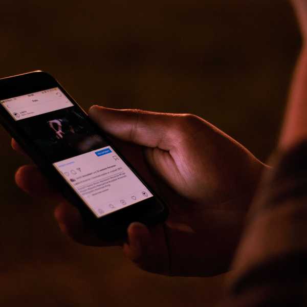 A person interacts with a smartphone in a dimly lit setting.