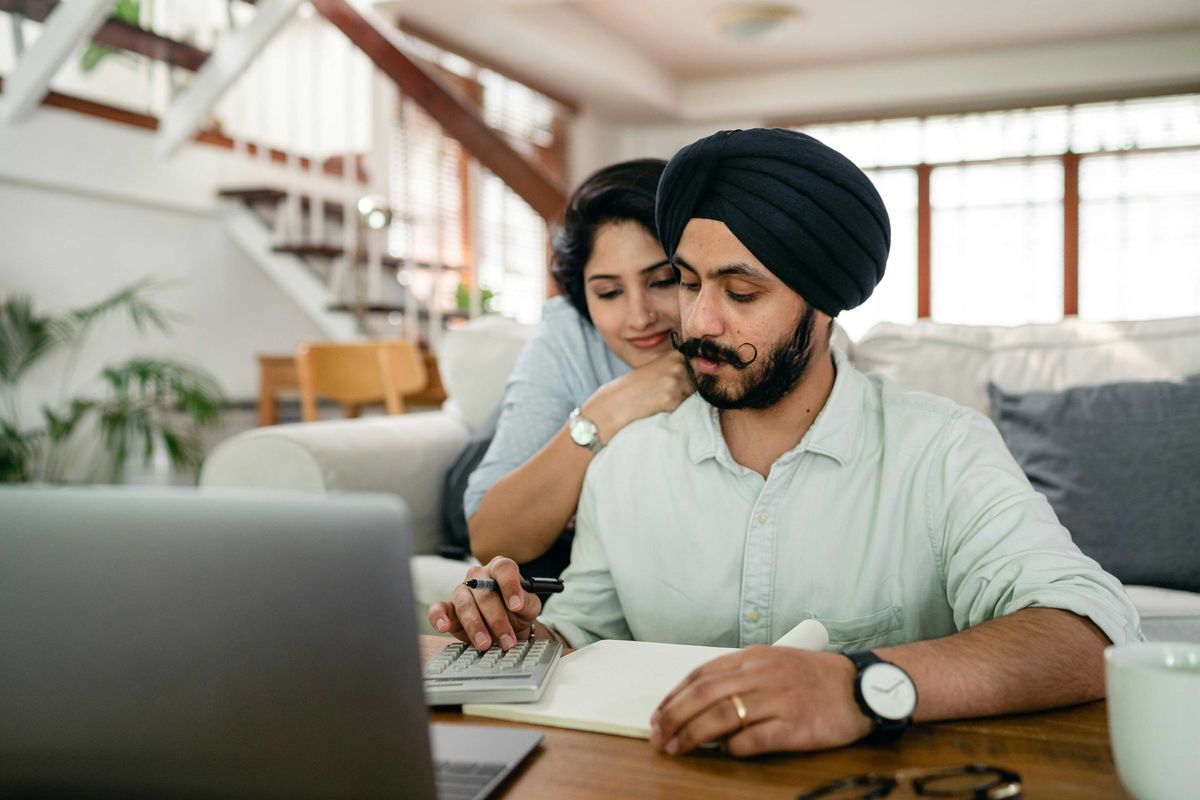 A South Asian couple reviews finances together at a home desk