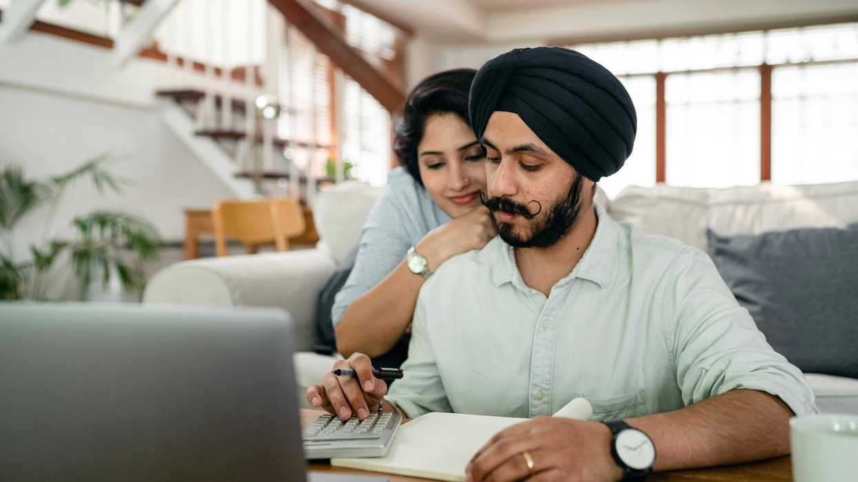 A South Asian couple reviews finances together at a home desk