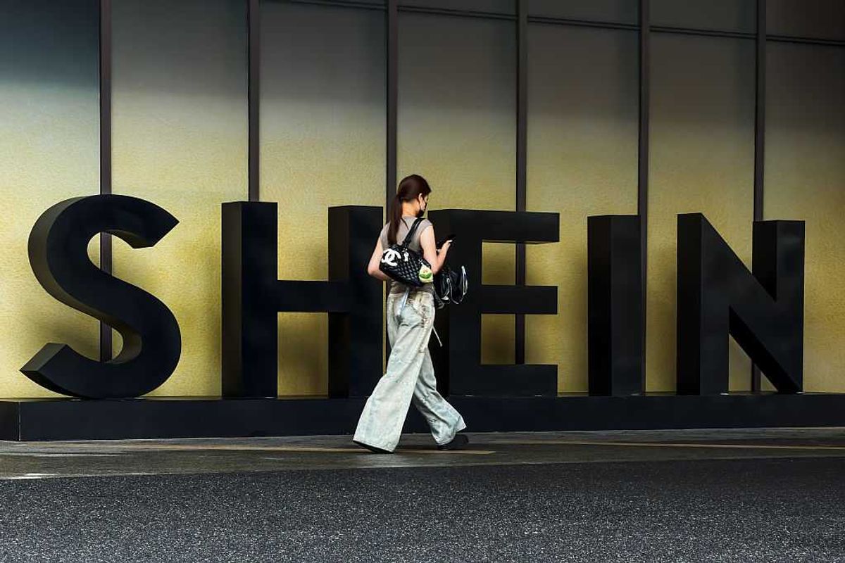 A woman carrying a Chanel bag walks in front of the Shein logo