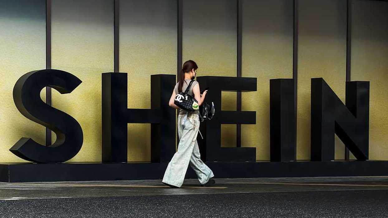 A woman carrying a Chanel bag walks in front of the Shein logo