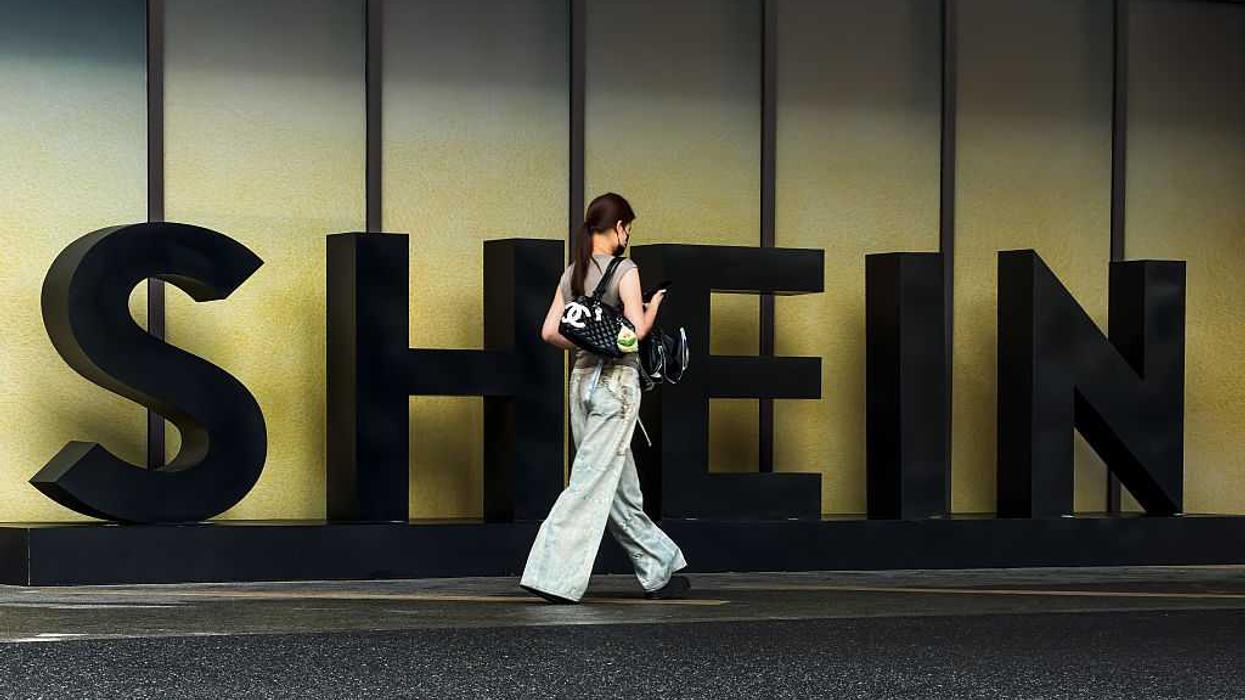 A woman carrying a Chanel bag walks in front of the Shein logo
