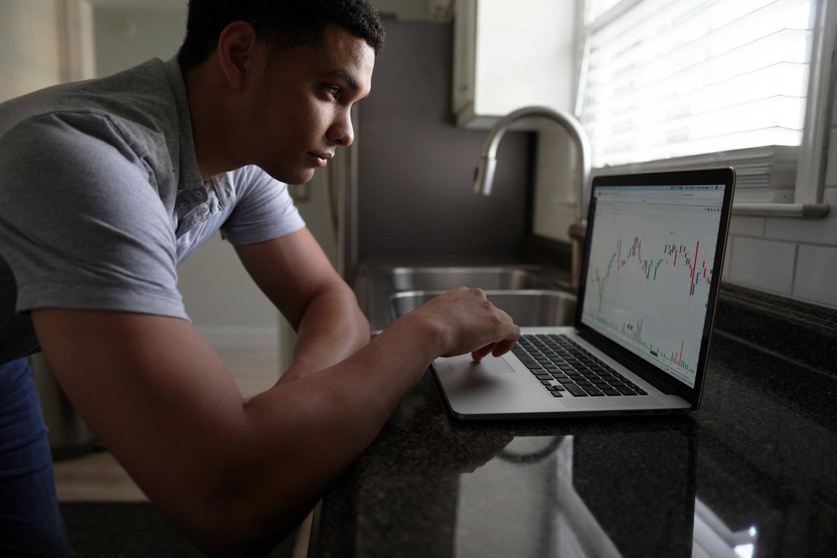 A young investor checks his portfolio on his computer at home