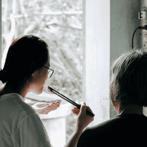 A younger asian woman uses chopsticks to taste a meal she cooks with an older relative