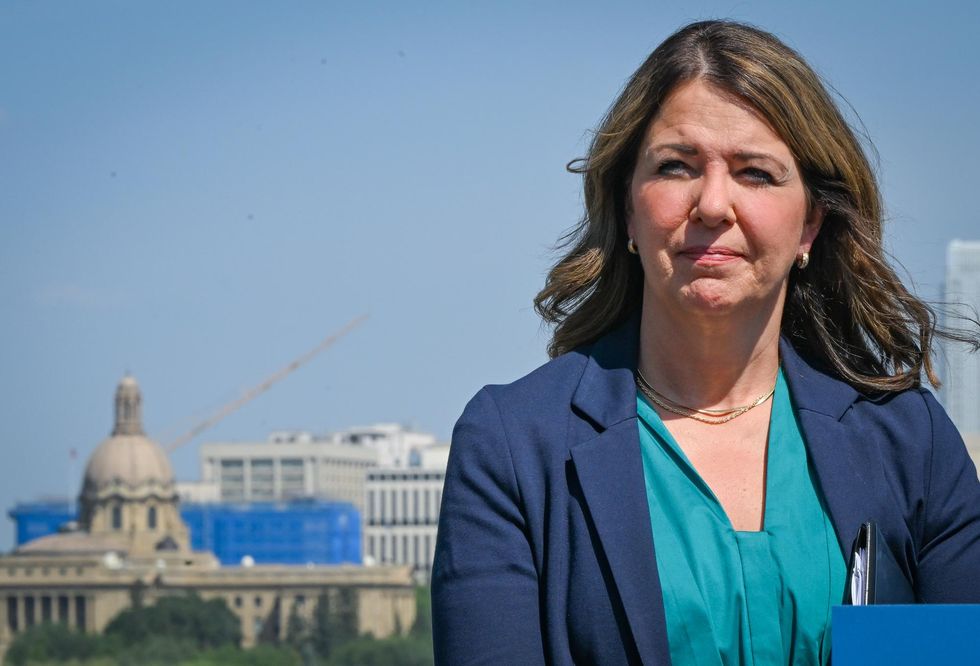 Alberta Premier Danielle Smith in blue blazer, with a domed legislative building behind her