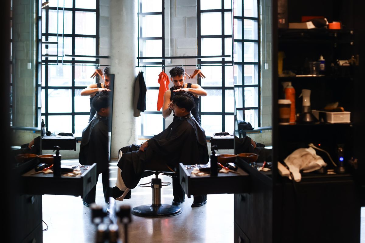 Barber styling a man's hair in a bright, modern barbershop