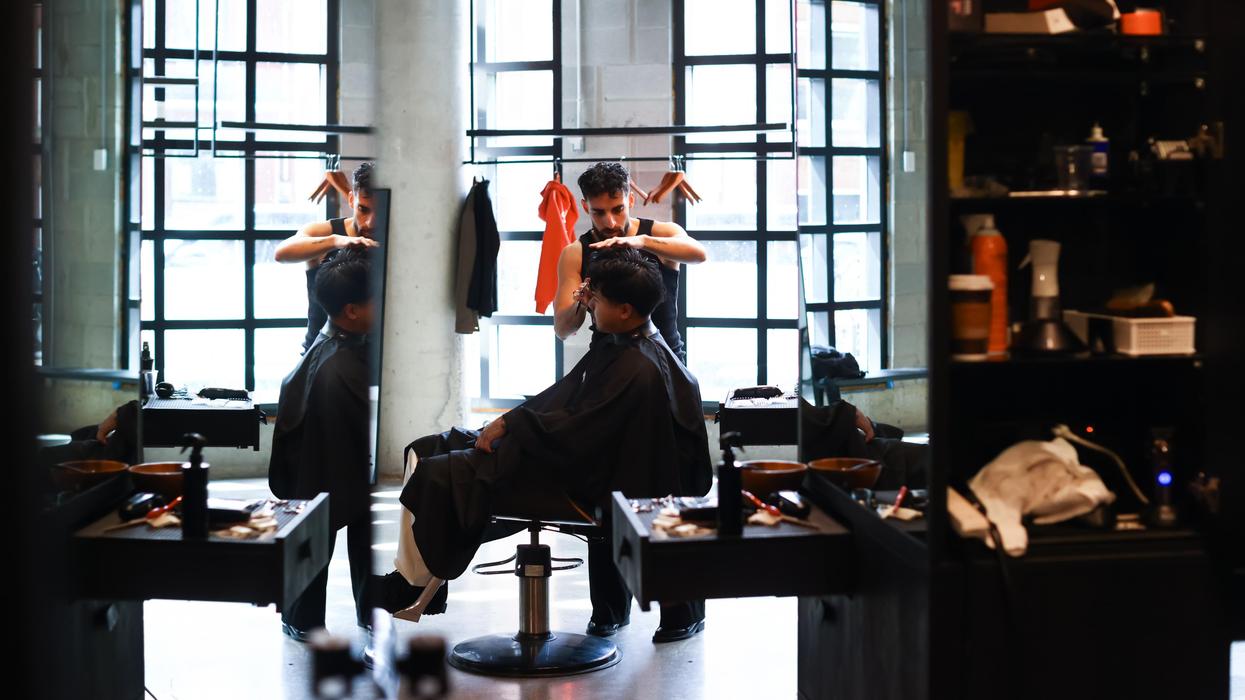 Barber styling a man's hair in a bright, modern barbershop