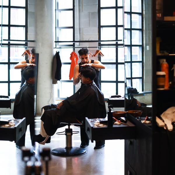 Barber styling a man's hair in a bright, modern barbershop
