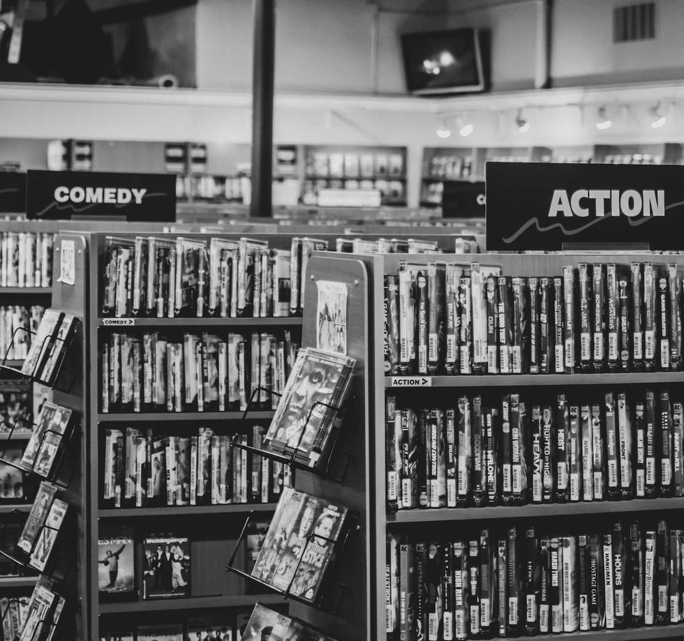 Black and white photo of a used movie store with shelves of DVDs in various genres