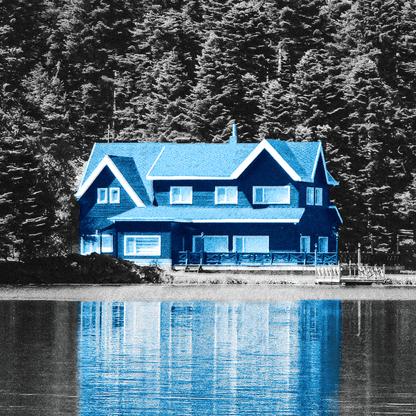 Blue house reflected in a lake, against a grayscale forest