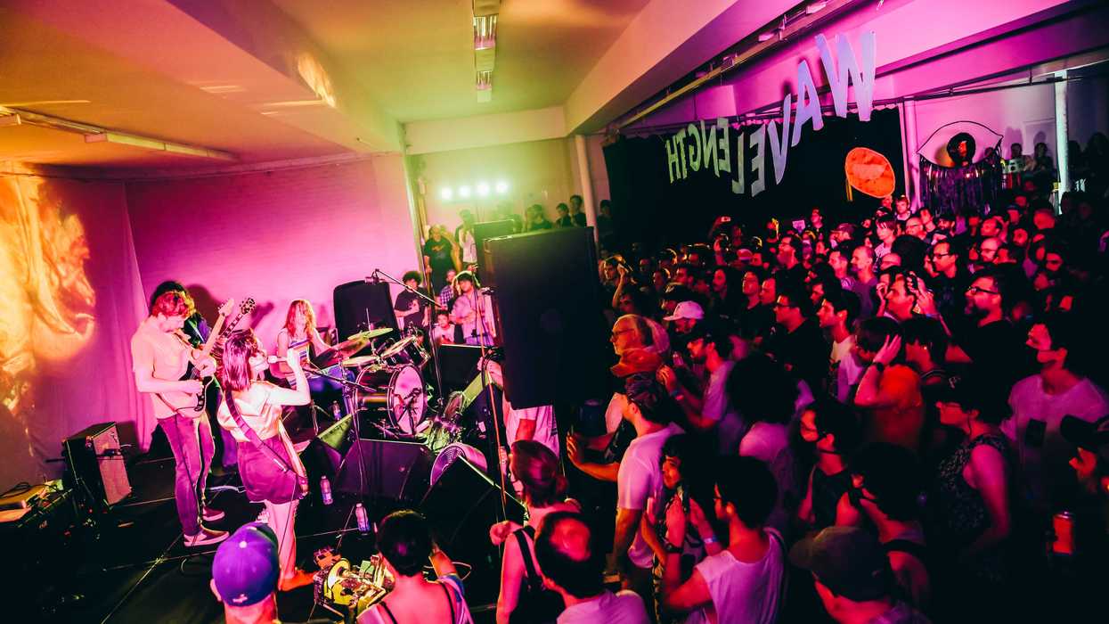 Deerhoof performs in a crowded indoor space.