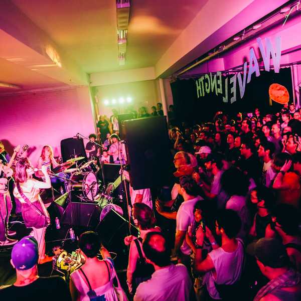 Deerhoof performs in a crowded indoor space.