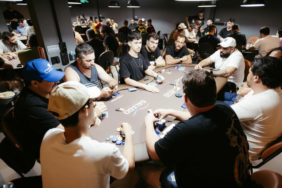 Dozens of poker players sit around the table to play in a tournament