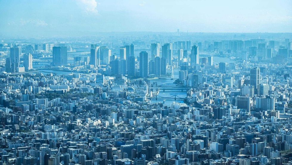 Expansive blue aerial view of Tokyo, a dense metropolis with skyscrapers, a river, and bridges
