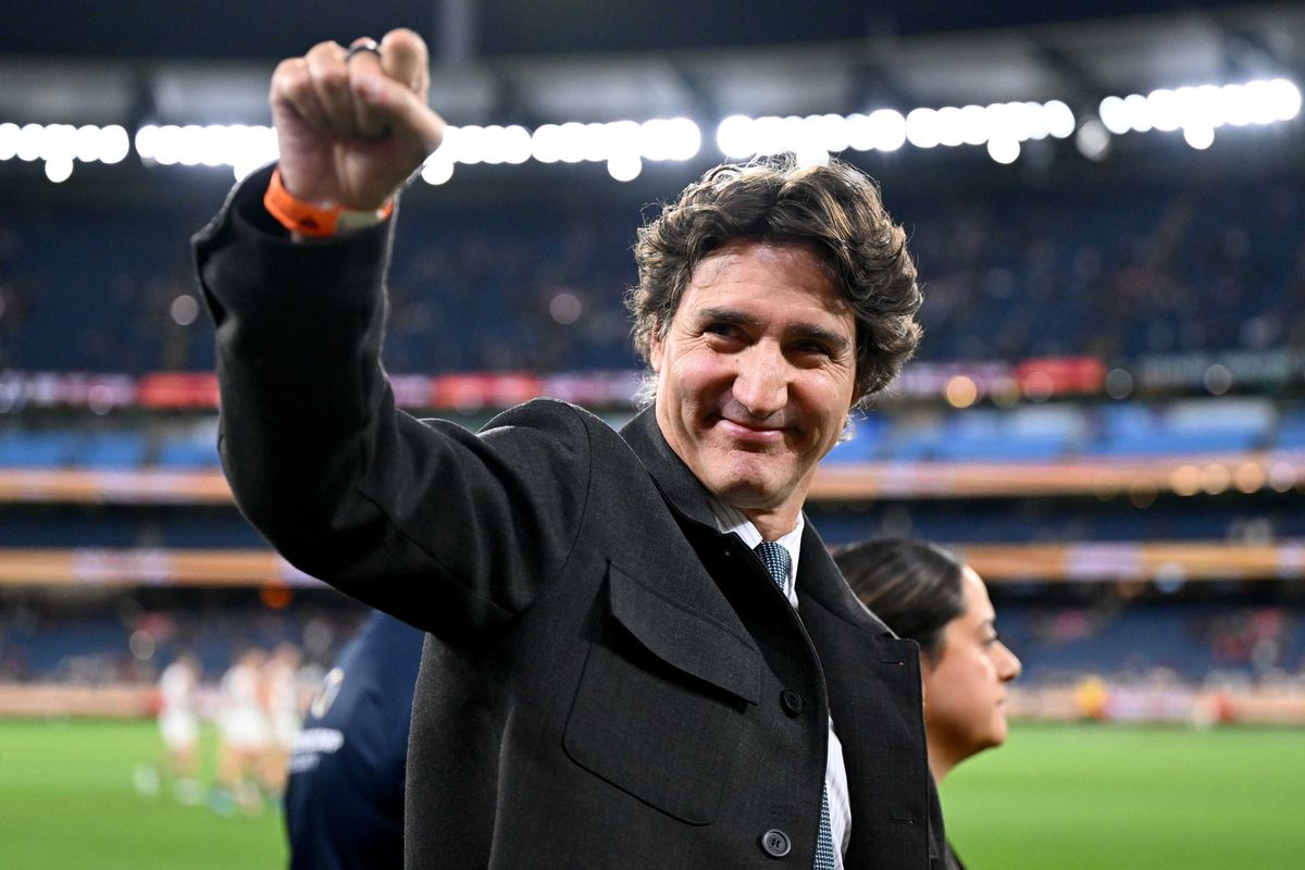Justin Trudeau makes a fist in the air in a sports stadium.
