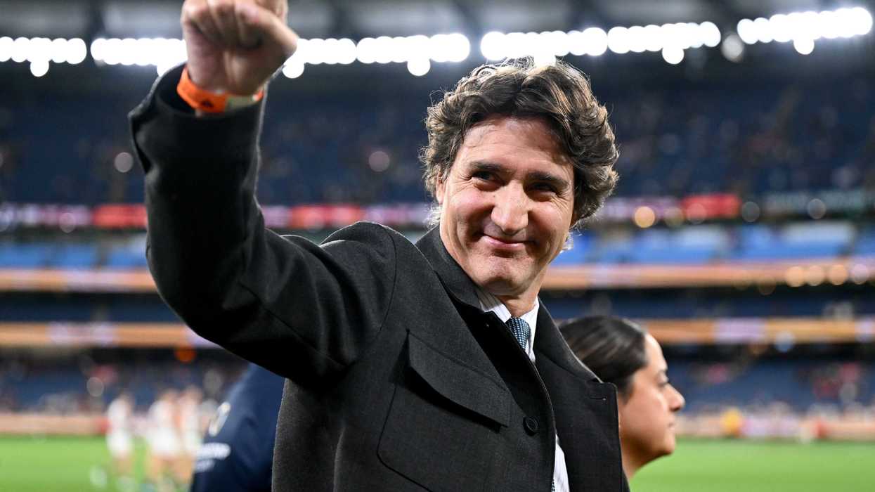 Justin Trudeau makes a fist in the air in a sports stadium.