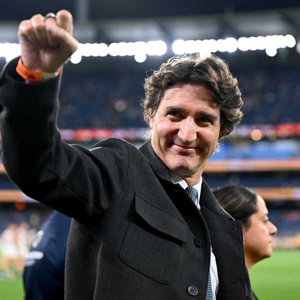 Justin Trudeau makes a fist in the air in a sports stadium.