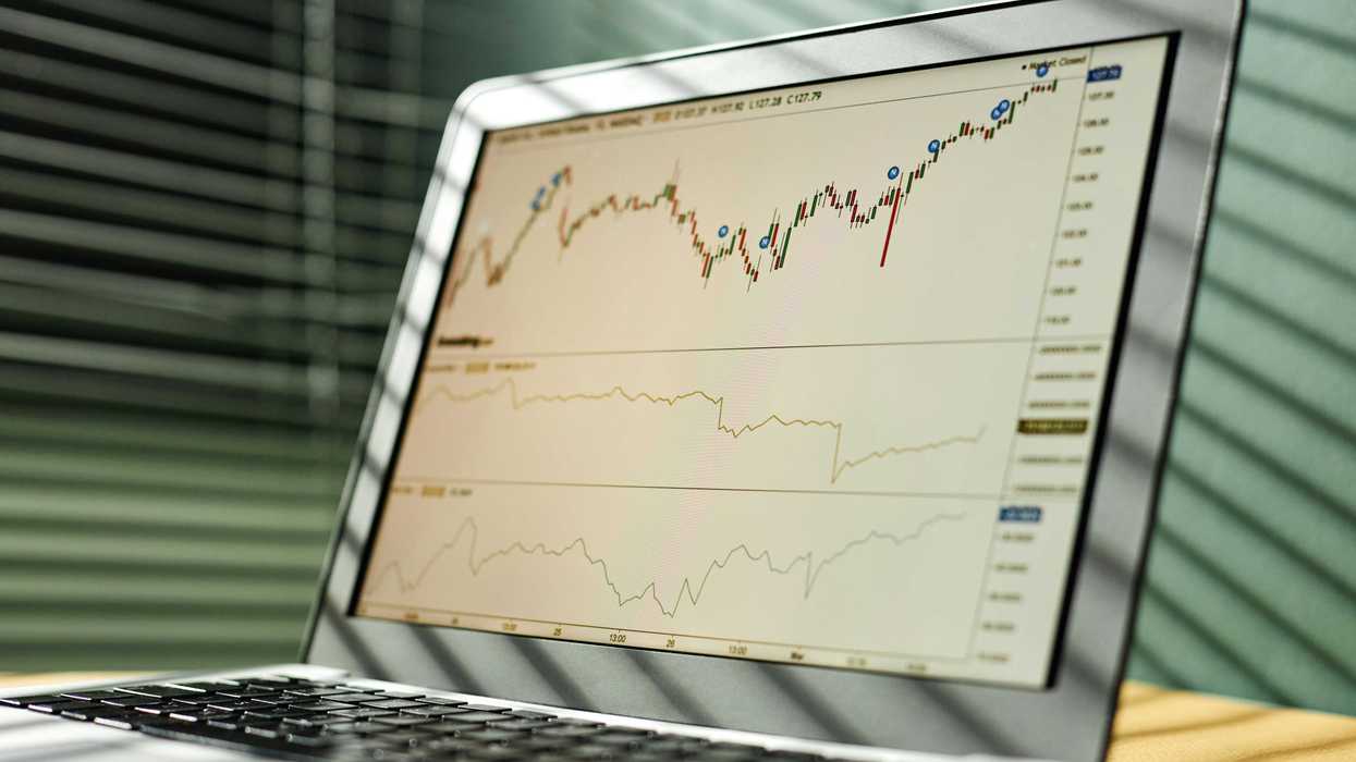 Laptop screen displaying stock market charts with candlestick and line graphs.