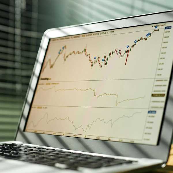 Laptop screen displaying stock market charts with candlestick and line graphs.