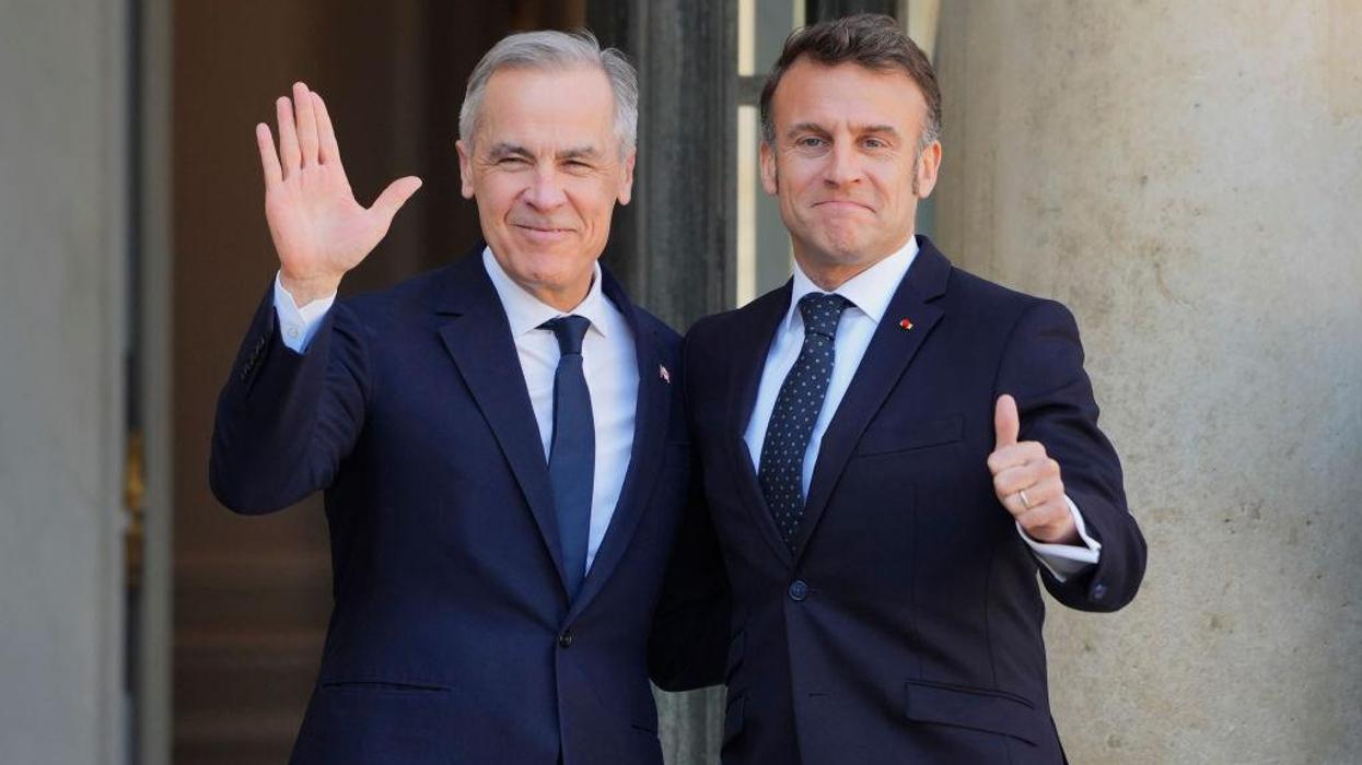 Mark Carney and Emmanuel Macron stand together and wave