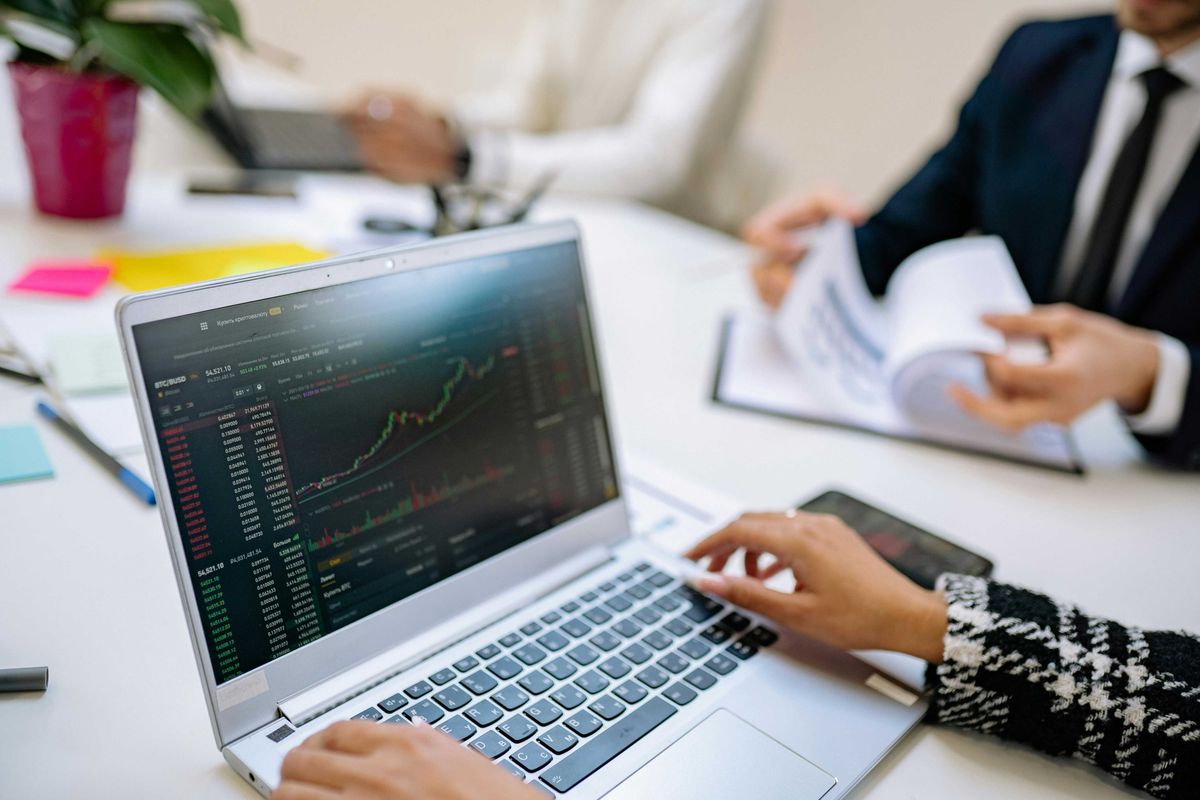 Person analyzing stock charts on a laptop at a business meeting