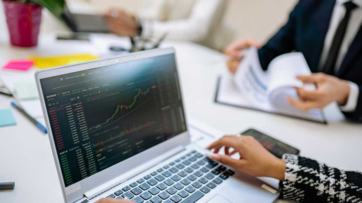 Person analyzing stock charts on a laptop at a business meeting