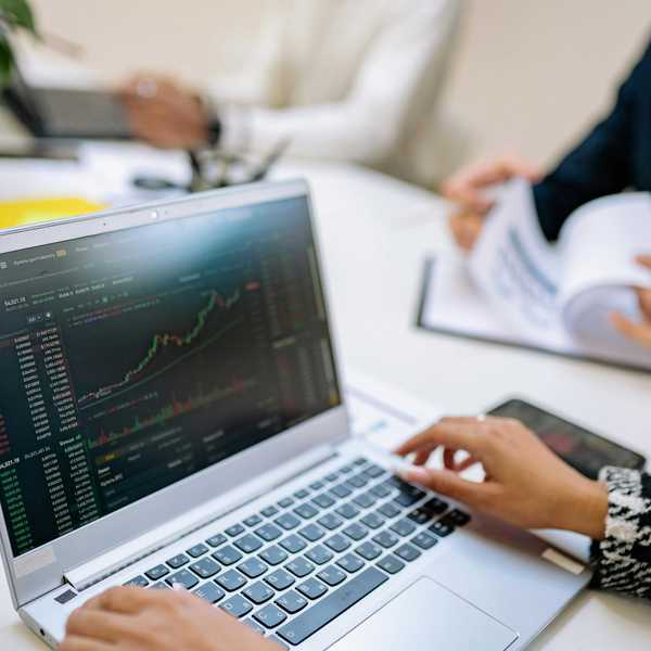 Person analyzing stock charts on a laptop at a business meeting