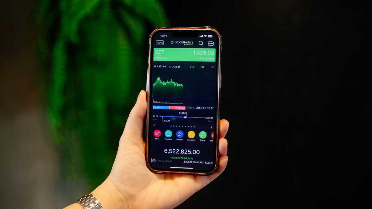 Person's hand holding a phone showing their investment app activity