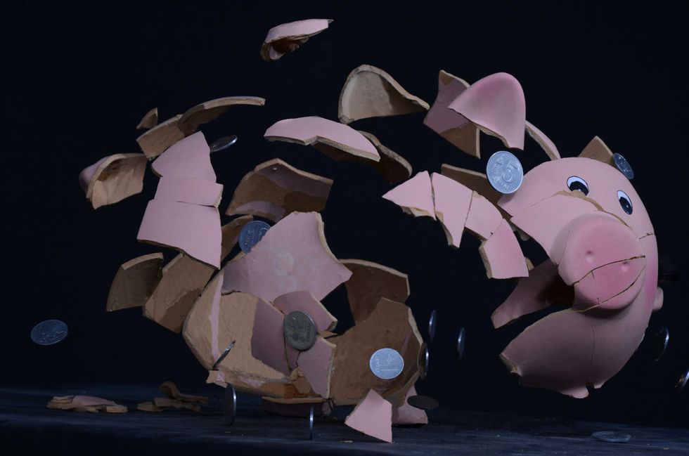 Pink piggy bank shattering into pieces, coins flying out against a dark background