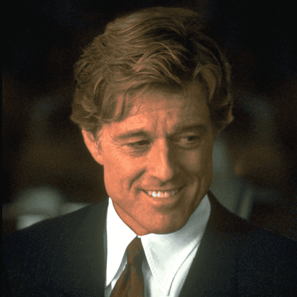 Robert Redford smiling in a dark suit and tie