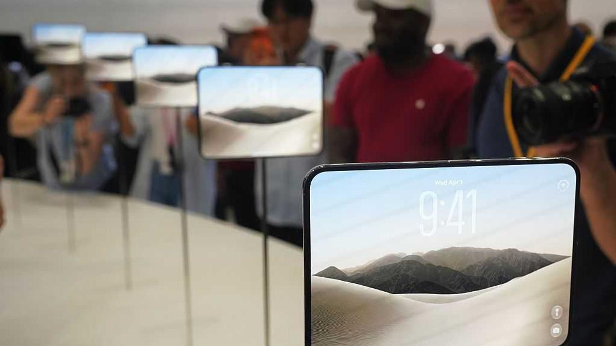 Several folding iPhone Duos on display on a table as people take photos