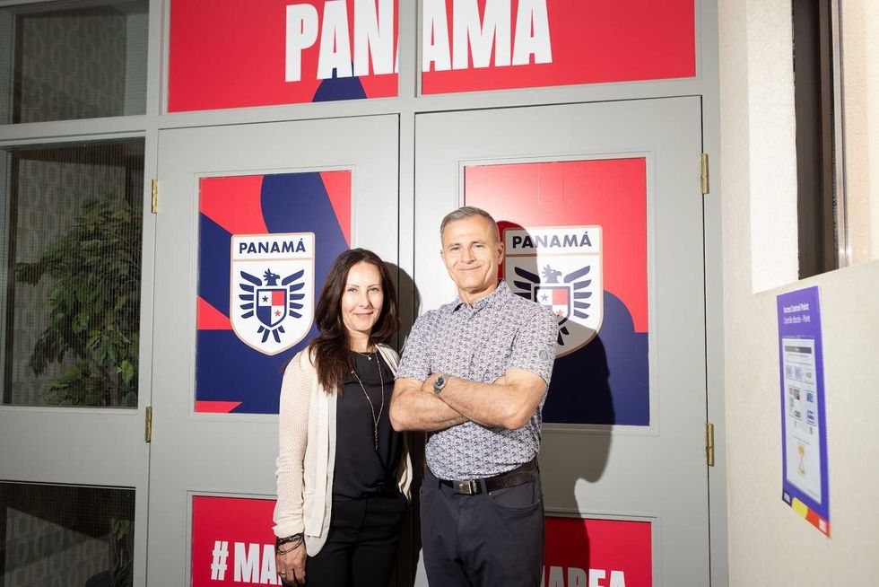 Sylvia and Dino Biffis stand in front of Team Panama's signage