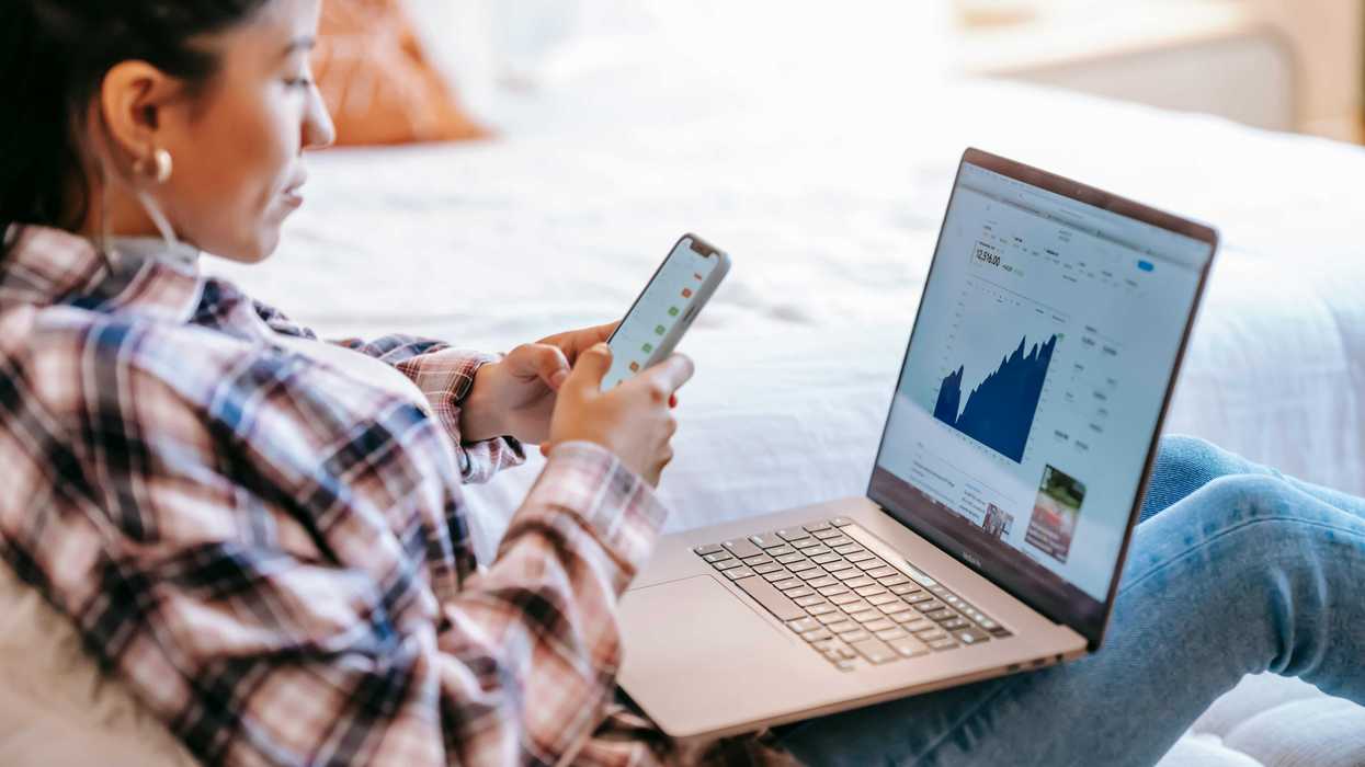 Woman analyzing financial charts on laptop and phone