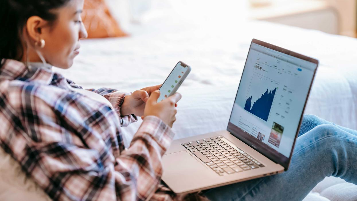 Woman analyzing financial charts on laptop and phone