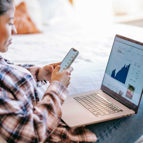 Woman analyzing financial charts on laptop and phone