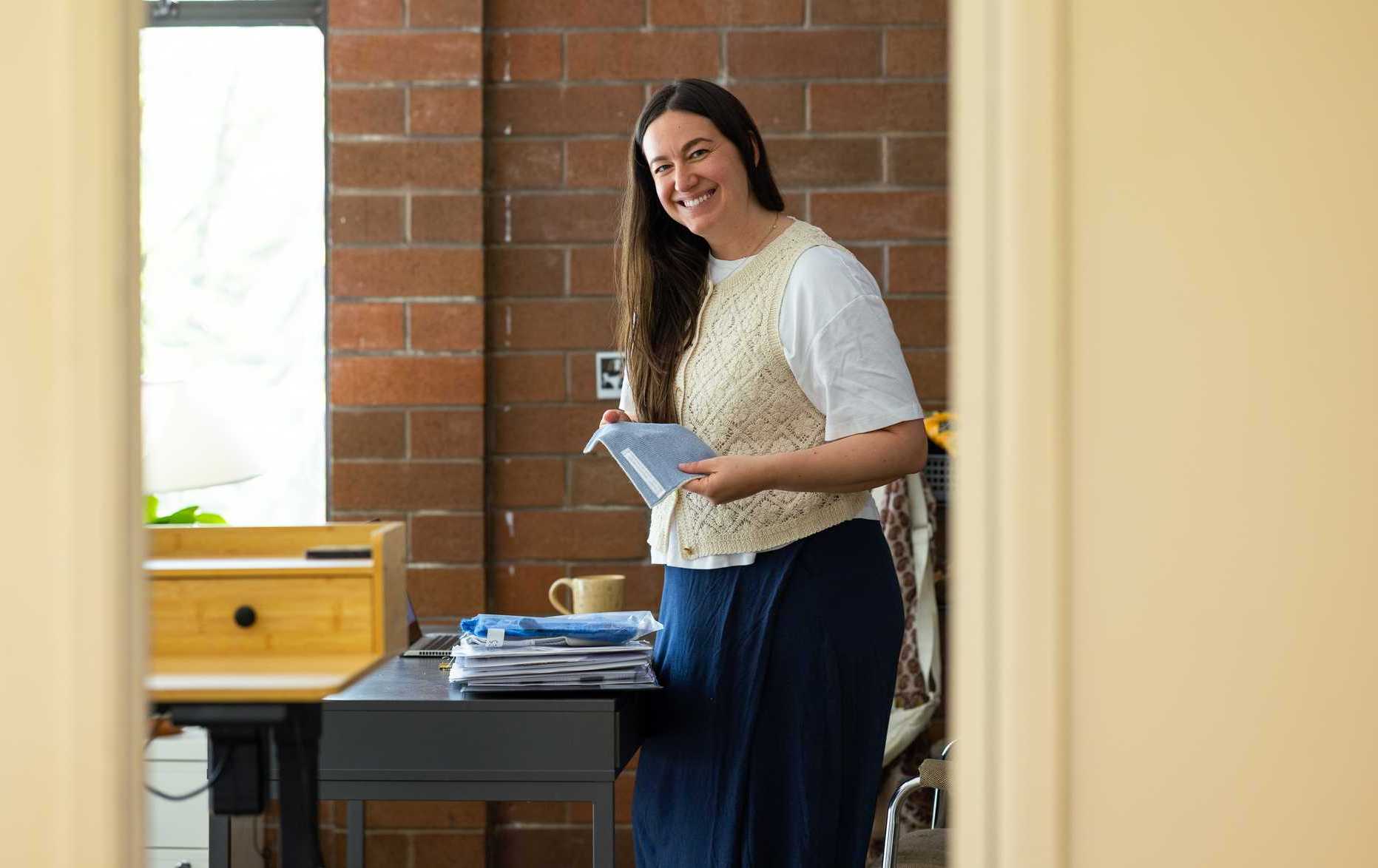 Woman smiles while holding fabric samples at a clothing company
