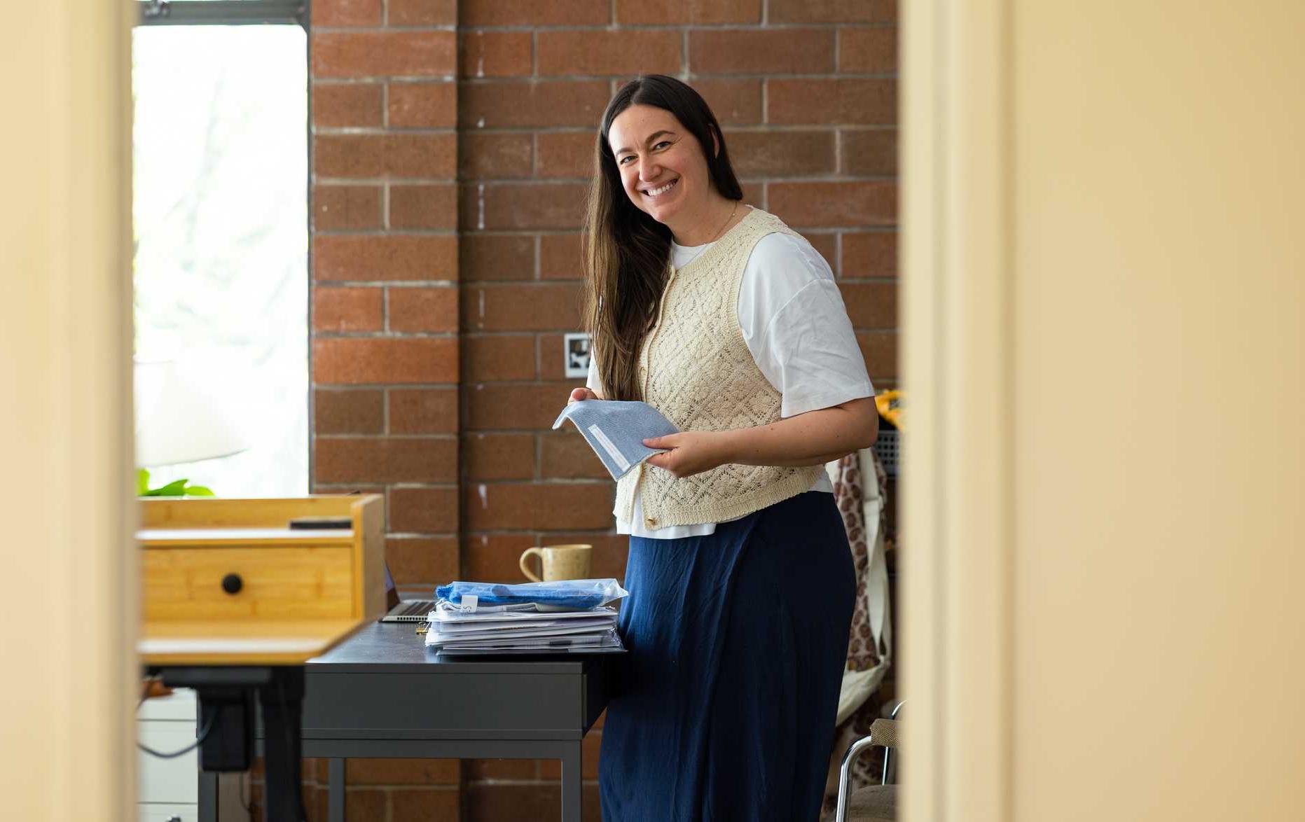 Woman smiles while holding fabric samples at a clothing company